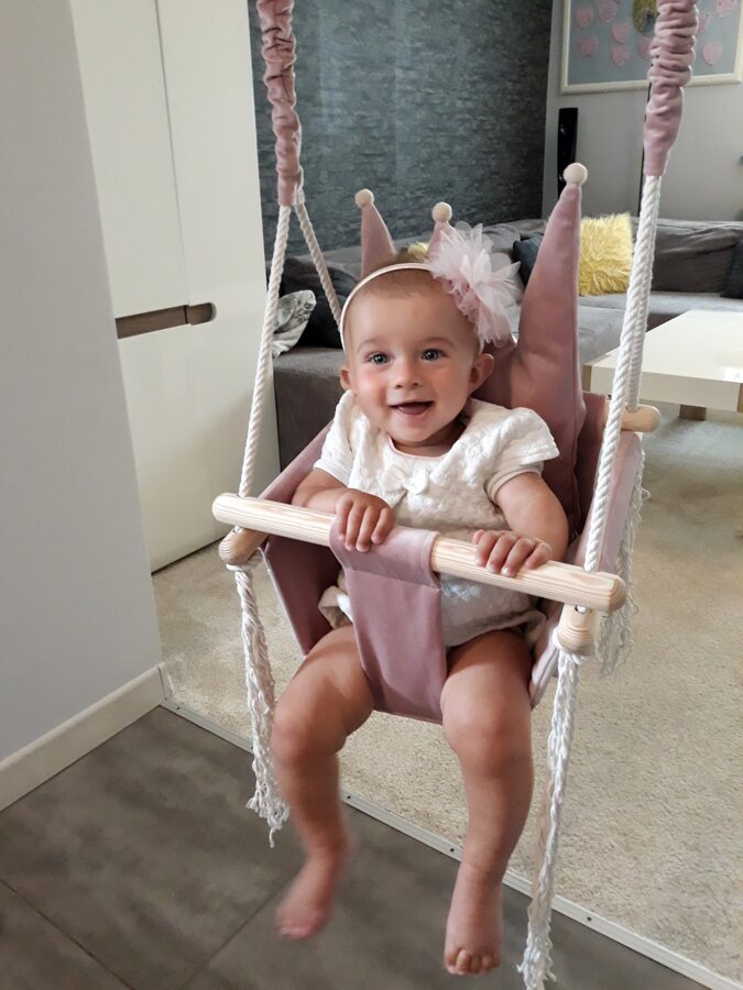 Soft handmade pale pink bear-patterned blanket draped over chair in cozy baby room