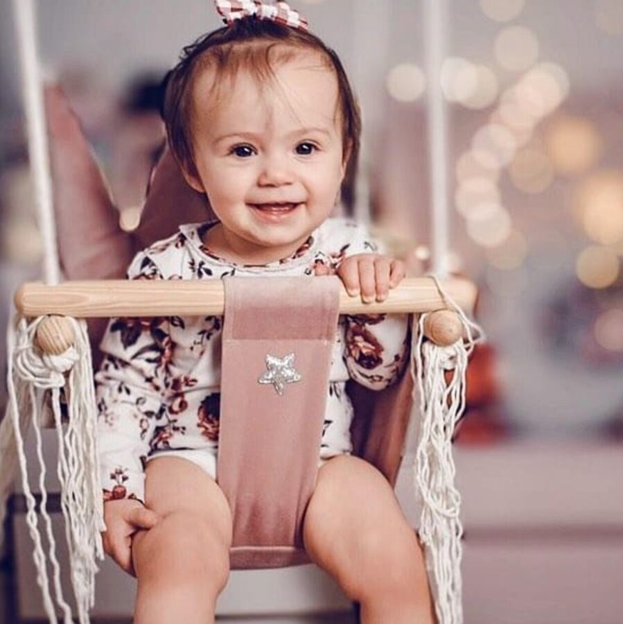 Soft handmade pale pink teddy pattern blanket draped on chair in cozy baby nursery